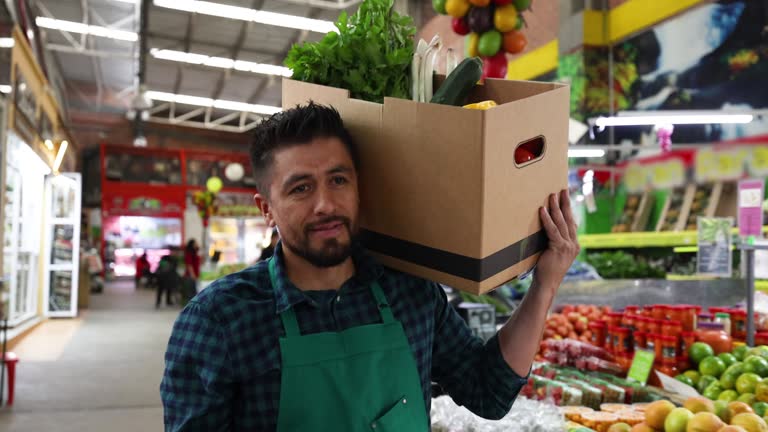 Male vendor at a farmer’s market carrying a subscription box on shoulder ready to get delivered to a customer