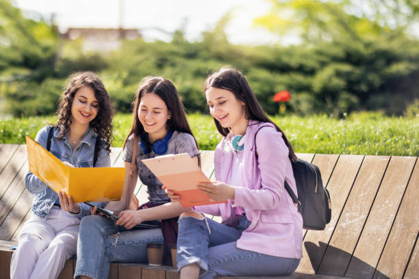 istock Group of collage students sitting on bench and studying for school 1487125908