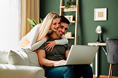 Beautiful young happy couple having video call via laptop at home