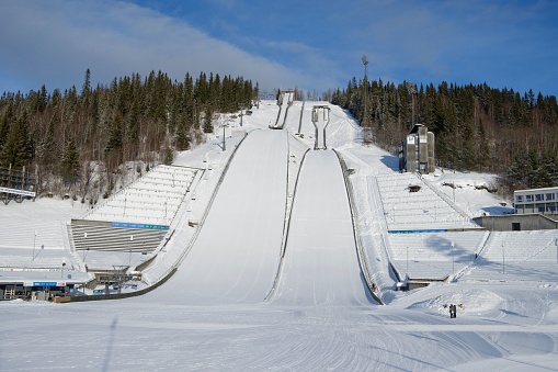 On the summer slope of the mountain, the construction of a roller coaster attraction against the background of green grass. On the right is a ski lift