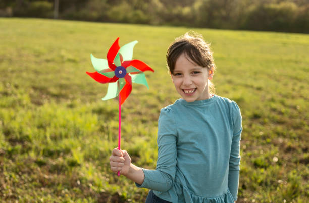 istock Cute little girl with a windmill standing on a meadow during spring day 1487129281