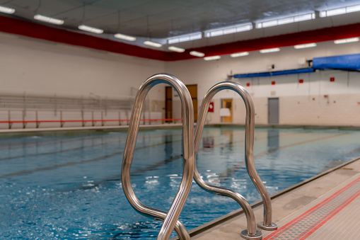 Stainless steel natatorium / swimming pool ladder with hand rails at in inside public swimming pool.