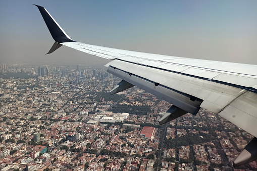 View on Mexico city through airplane window of commercial jet plane landing in local airport. Air travelling concept.