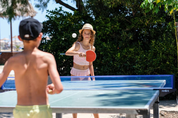 a boy and a girl play table tennis at the sea