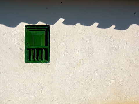 Detail of a little green wooden window in an old farmhouse at sunrise, near the town of Arcabuco in the central Andean mountains of Colombia.