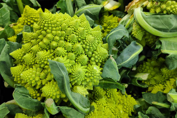 стопка брокколи романеско на рыночном прилавке - romanesco broccoli стоковые фото и изображения