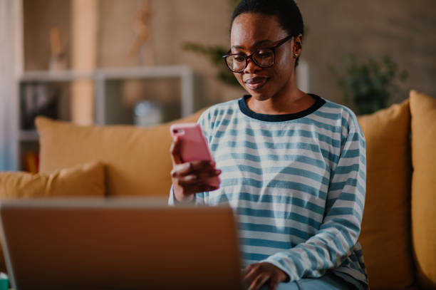 istock African american woman using laptop and a smartphone while sitting on a sofa at home 1487139788