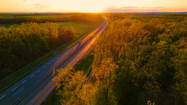 istock AERIAL Vehicles moving on glowing motorway surrounded with trees at sunset light 1487141311