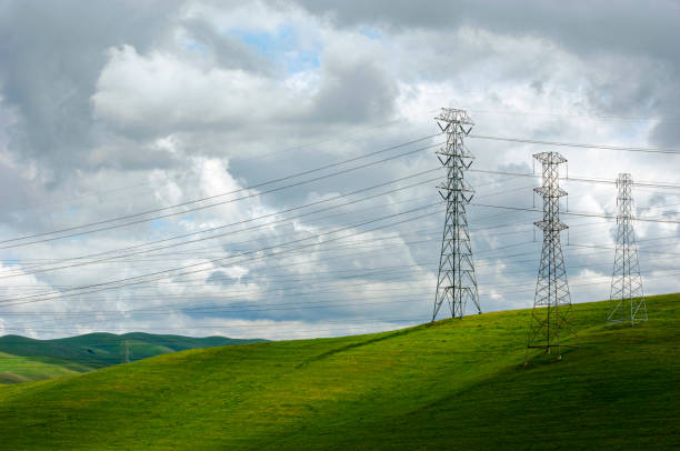 Wide view of power pylons and power lines under a cloudy sky.