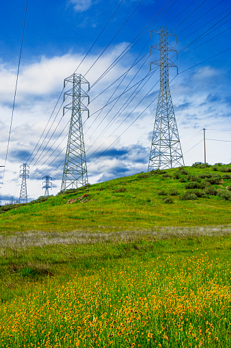 Wide view of power pylons and power lines under a cloudy sky.
