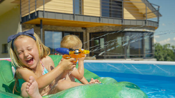 istock CLOSE UP: Smiling kids having fun at pool party while splashing with water gun 1487141454