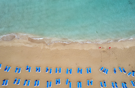 Symmetrically placed beach chairs on clean white sand in Italy. Brands retouched, no further edit. Soft shadows, photo taken from above. Symbolic for holiday.