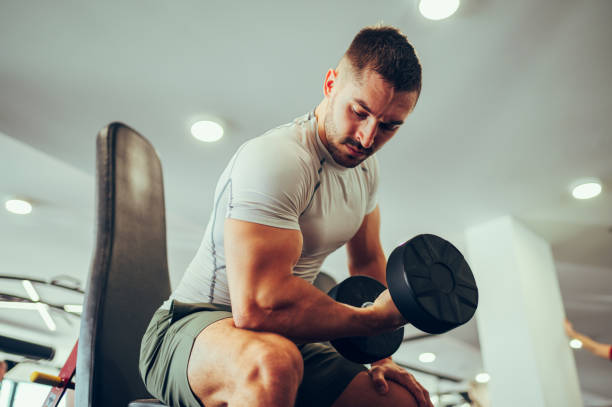 istock Low angle view of a strong weightlifter pumping biceps while lifting a dumbbell. 1487148954