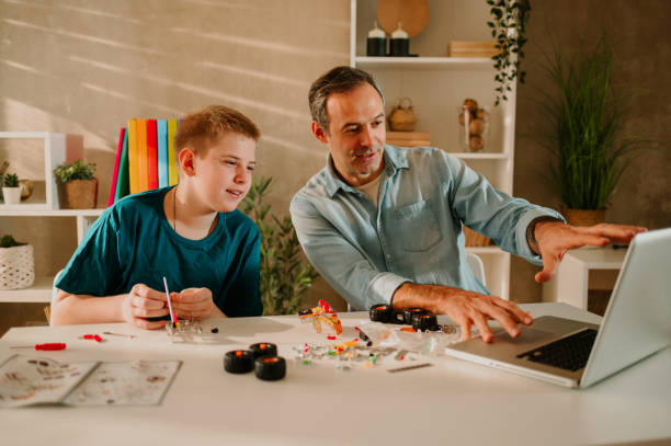 istock Young boy and his father sitting down together and browsing the internet. 1487148985