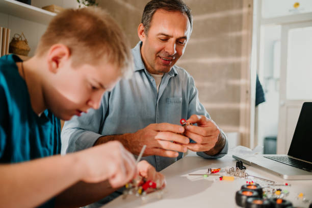 istock Cheerful father helping his teenage son while assembling the toy together. 1487148987