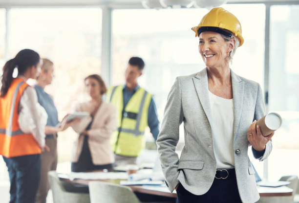 istock Senior architect, leader woman and office with drawing, team or vision for construction project for property. Architecture agency, engineer expert and paper for blueprint, innovation and design goals 1487149194