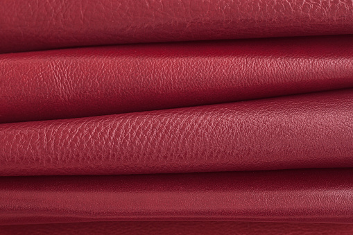 Rolled colorful dark red leather samples, fashion industry concept. Palette collection close up, background