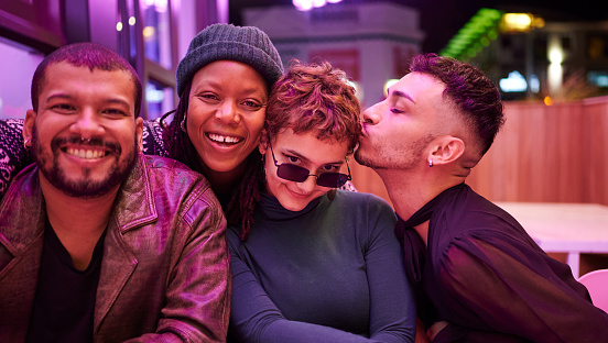 Portrait of a diverse group of young friends laughing while having a fun night out together in the city