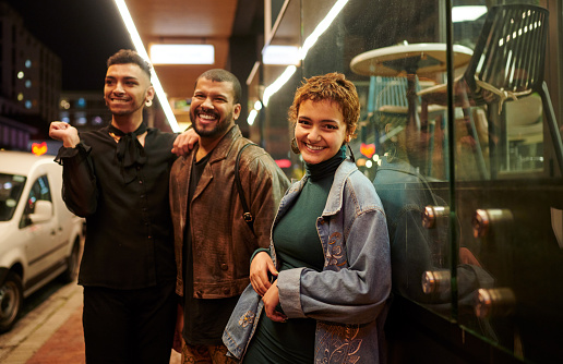 Portrait of a diverse group of a stylish young friends standing together on a sidewalk during a night out in the city