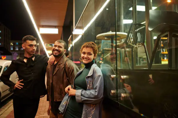 Portrait of a stylish group of a diverse young friends standing together on a sidewalk during a night out in the city