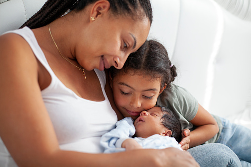 African-American mother with daughter and newborn son in the bed