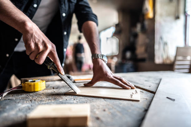 close-up of a man carving wood with chisel and hammer at carpentry - carpenter restoring furniture wood imagens e fotografias de stock