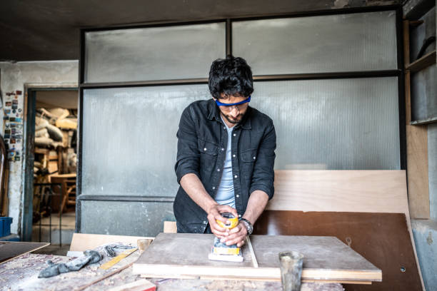 istock Mid adult carpenter using sander while working on a piece of wood at carpentry workshop 1487158146