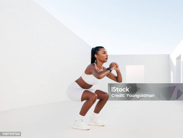 Female Fitness Influencer Doing Situps In A White Outdoor Studio Young Woman Doing Workout Outdoors Female In White Fitness Attire Is Doing Exercises For Her Glutes Stock Photo - Download Image Now
