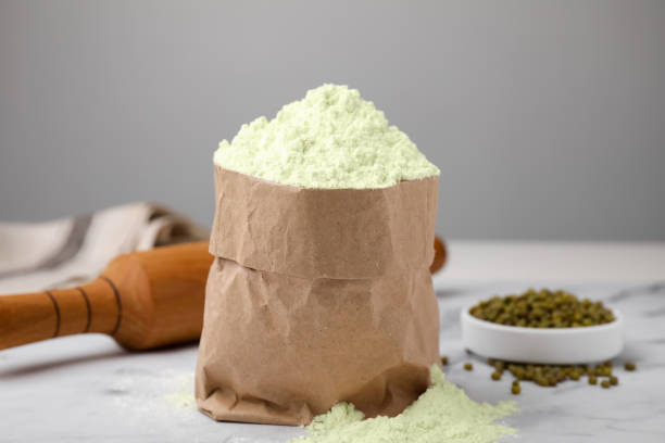 istock Mung bean flour in paper bag and seeds on white marble table 1487161249