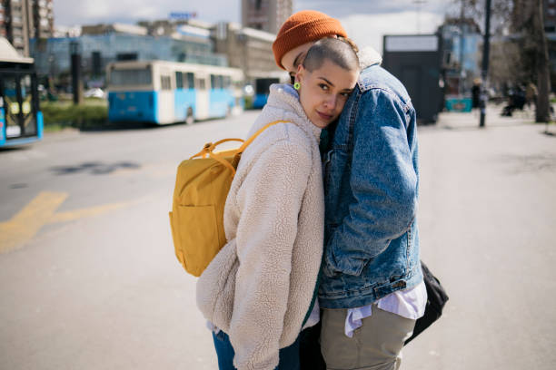 Female friends greeting each other good bye with a hug outside in the city stock photo