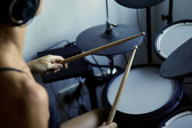 A young woman with headphones playing the drums