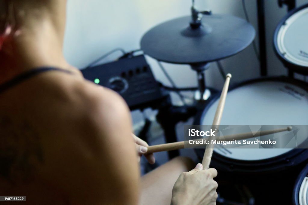 Young woman playing an electronic drum kit Young woman holding crossed drumsticks Drum - Percussion Instrument Stock Photo