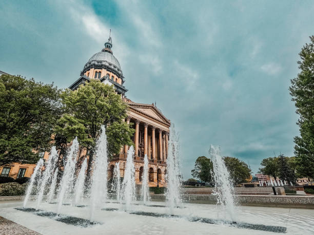 Views of the Illinois State Capitol Building in Springfield, Illinois, USA An ornamental water fountain sprays and splashes in front of the Illinois State Capitol Building. The majestic building stands tall on a Spring day with cloudy blue skies overhead. springfield illinois skyline stock pictures, royalty-free photos & images