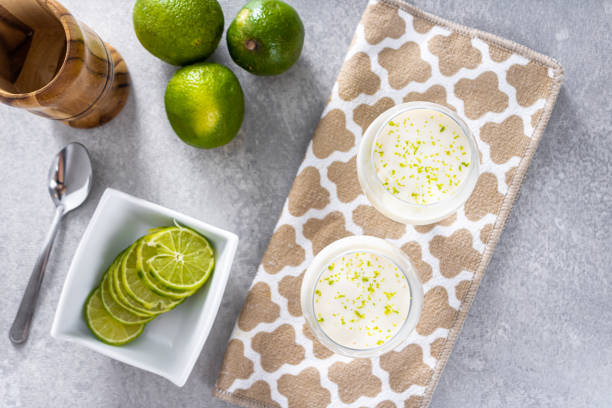 istock Delicious lemon mousse on a brown tablecloth and white table background, with whole and sliced lemons in the background, and a metal spoon 1487168914