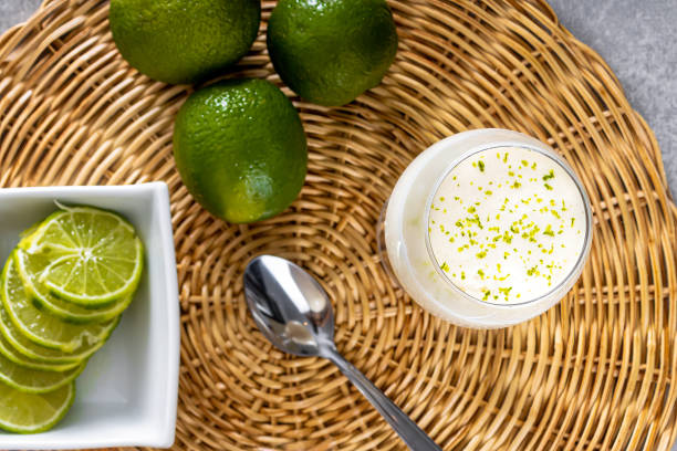 istock Delicious lemon mousse on a straw plate and a white table background, with whole and sliced lemons in the background, and a metal spoon 1487168924