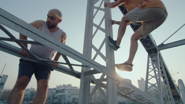 Two Parkour Athletes Climbing on City Bridge