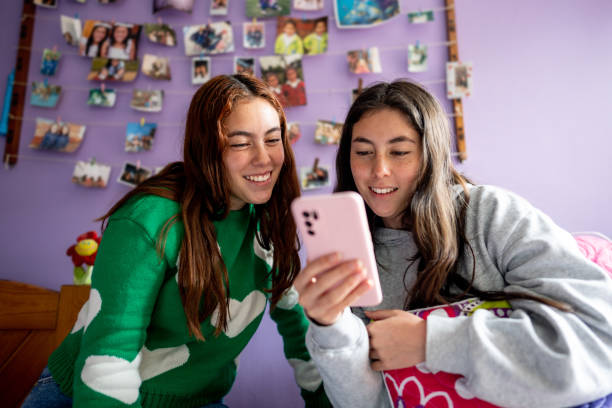istock Twin sisters using mobile phone on bedroom at home 1487170977