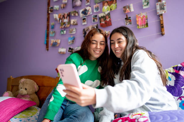 istock Twin sisters using mobile phone on bedroom at home 1487171493