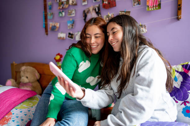 istock Twin sisters using mobile phone on bedroom at home 1487171503