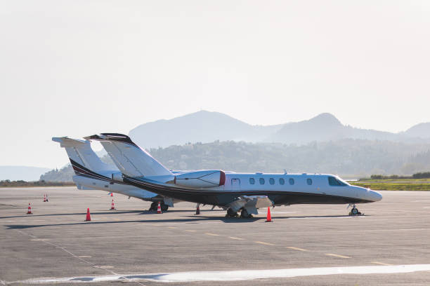 View of modern private reactive aircraft on an runway airfield ready to take off, airstrip with business jet airplane before the flight with mountains in the background in a summer sunny day stock photo