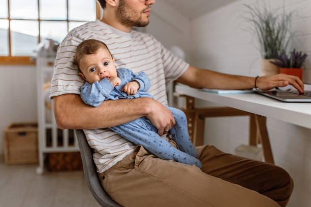 istock Young father holding baby boy and working using laptop at home 1487172970