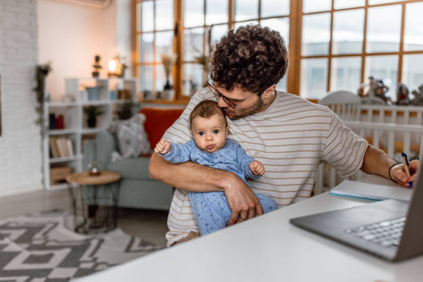 istock Young father holding baby boy and working using laptop at home 1487172974