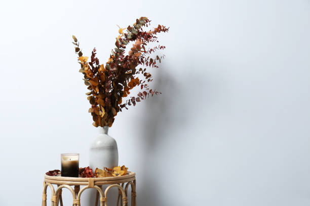 istock Vase with branches and candle on table near white wall, space for text 1487173180