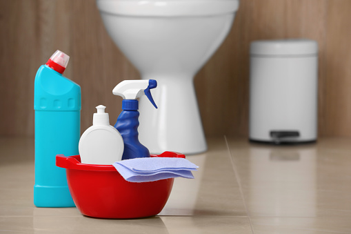 Different toilet cleaning supplies on floor indoors, space for text