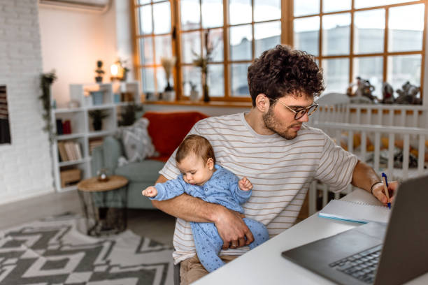 istock Young father holding baby boy and working using laptop at home 1487173402
