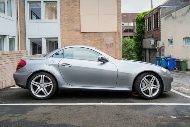 A gray colored second generation Mercedes SLK 200 is parked in a parking lot in Glasgow, Scotland on an overcast day.