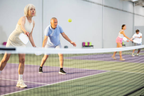 anciana jugando partido de pickleball en equipo con pareja masculina - deporte de raqueta fotografías e imágenes de stock