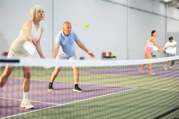 男性パートナーとチームでピックルボールの試合をする年配の女性 - tennis indoors women court ストックフォトと画像