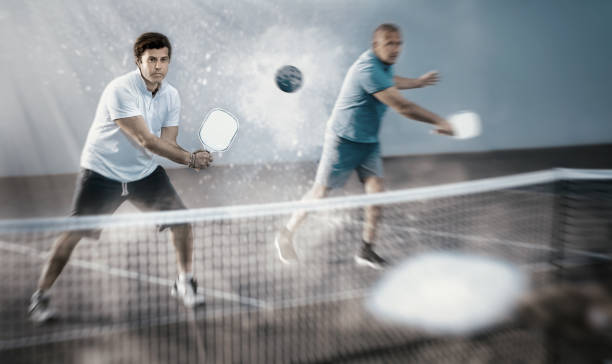 focused adult man playing pickleball match in team with older partner - tennis active seniors healthy lifestyle senior men imagens e fotografias de stock