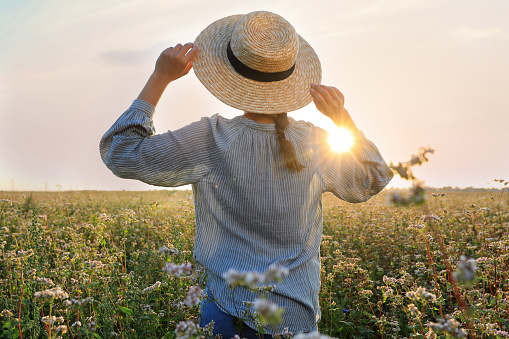 Woman with hat in beautiful blossoming buckwheat field